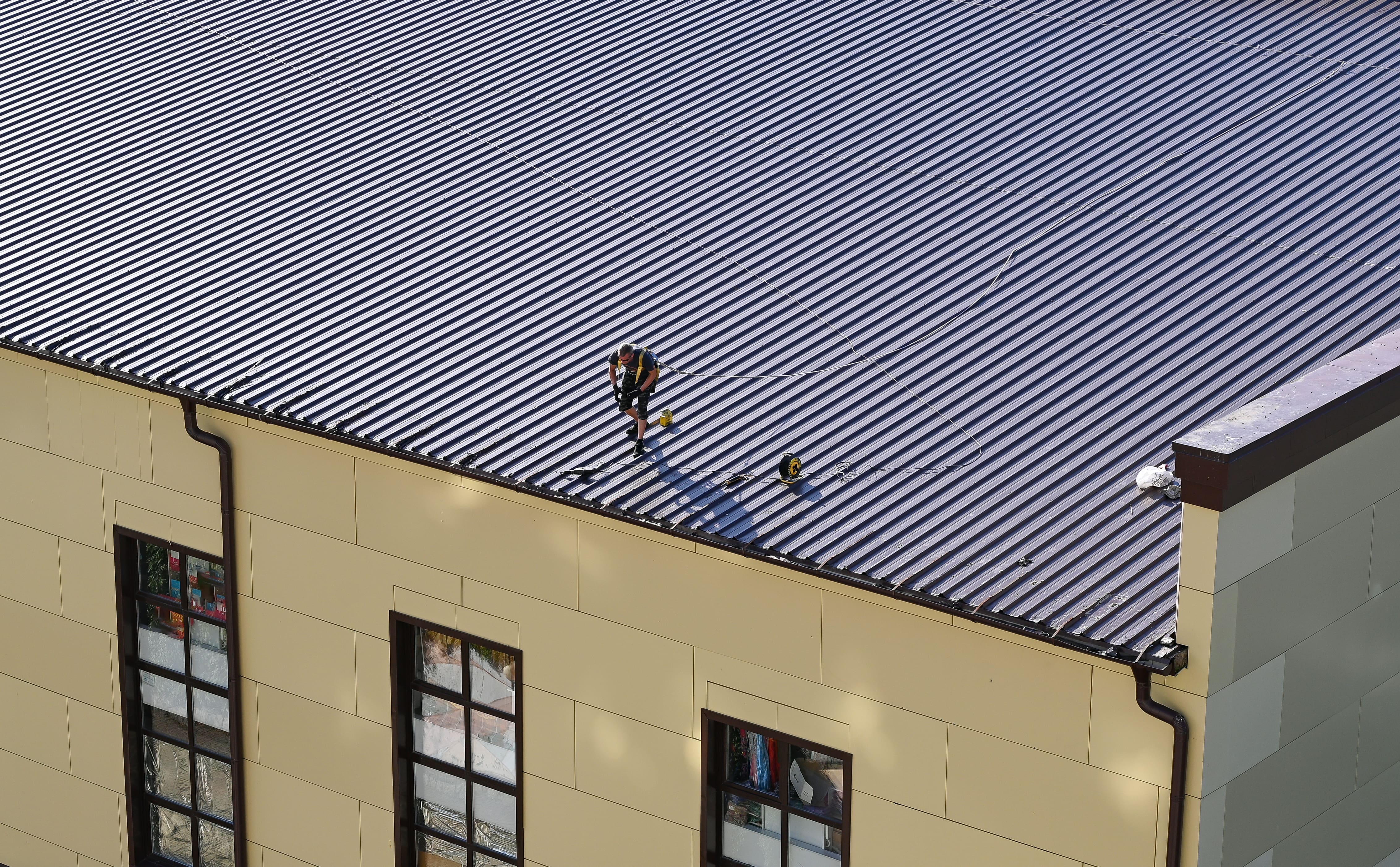 professional roof worker inspecting roof of a building