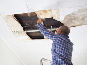 Man repairing collapsed ceiling. Ceiling panels damaged huge hole in roof from rainwater leakage.Water damaged ceiling .