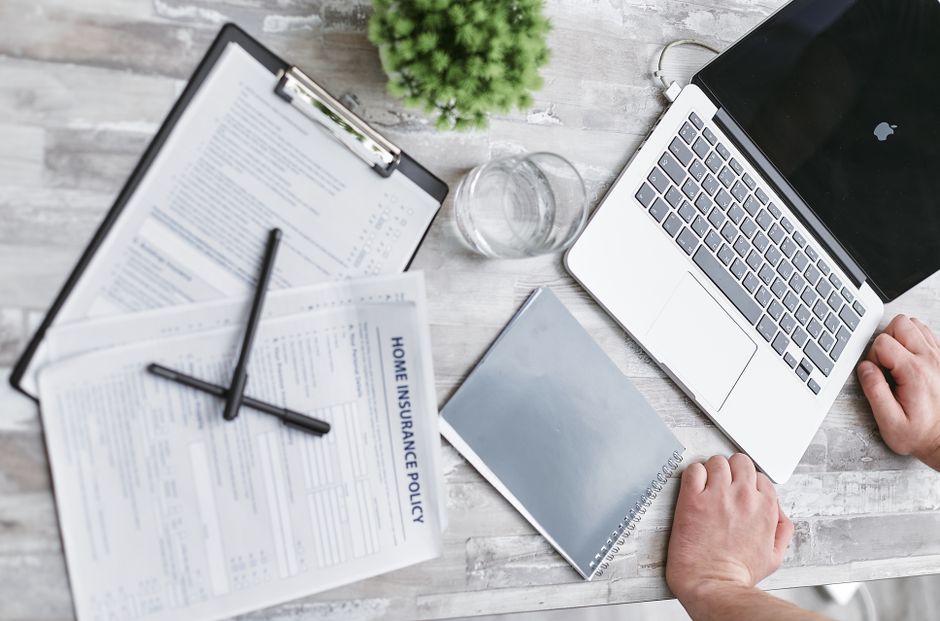 Homeowner reviewing roof insurance claim documents and estimates at the kitchen table