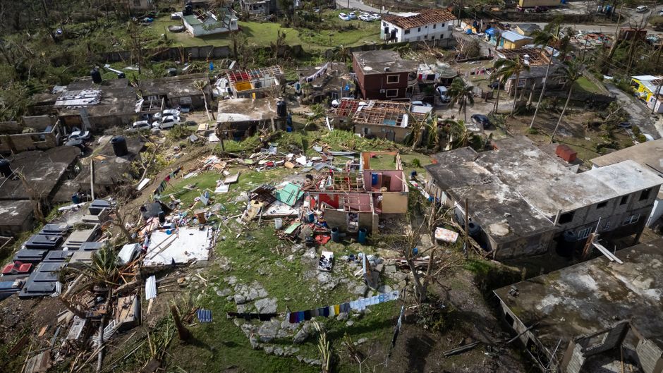 Aerial view of hurricane and wind storm damage across a residential neighborhood roofline